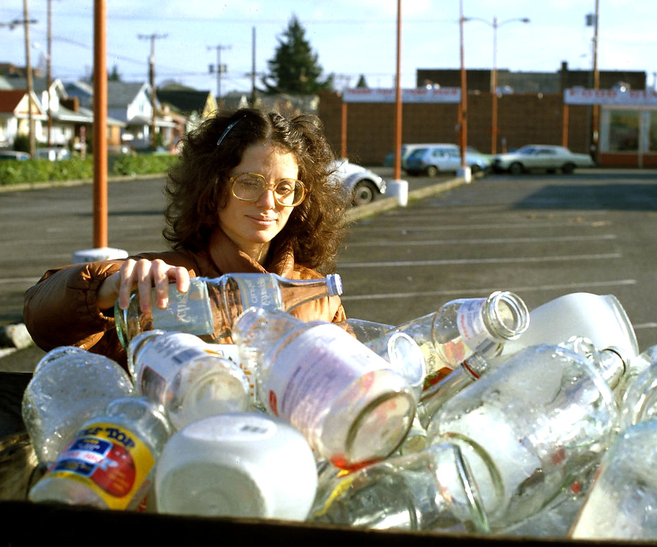 A woman recycles a glass bottle